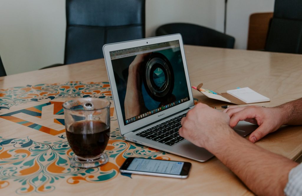 A man works at a laptop on a desk with a cup of coffee