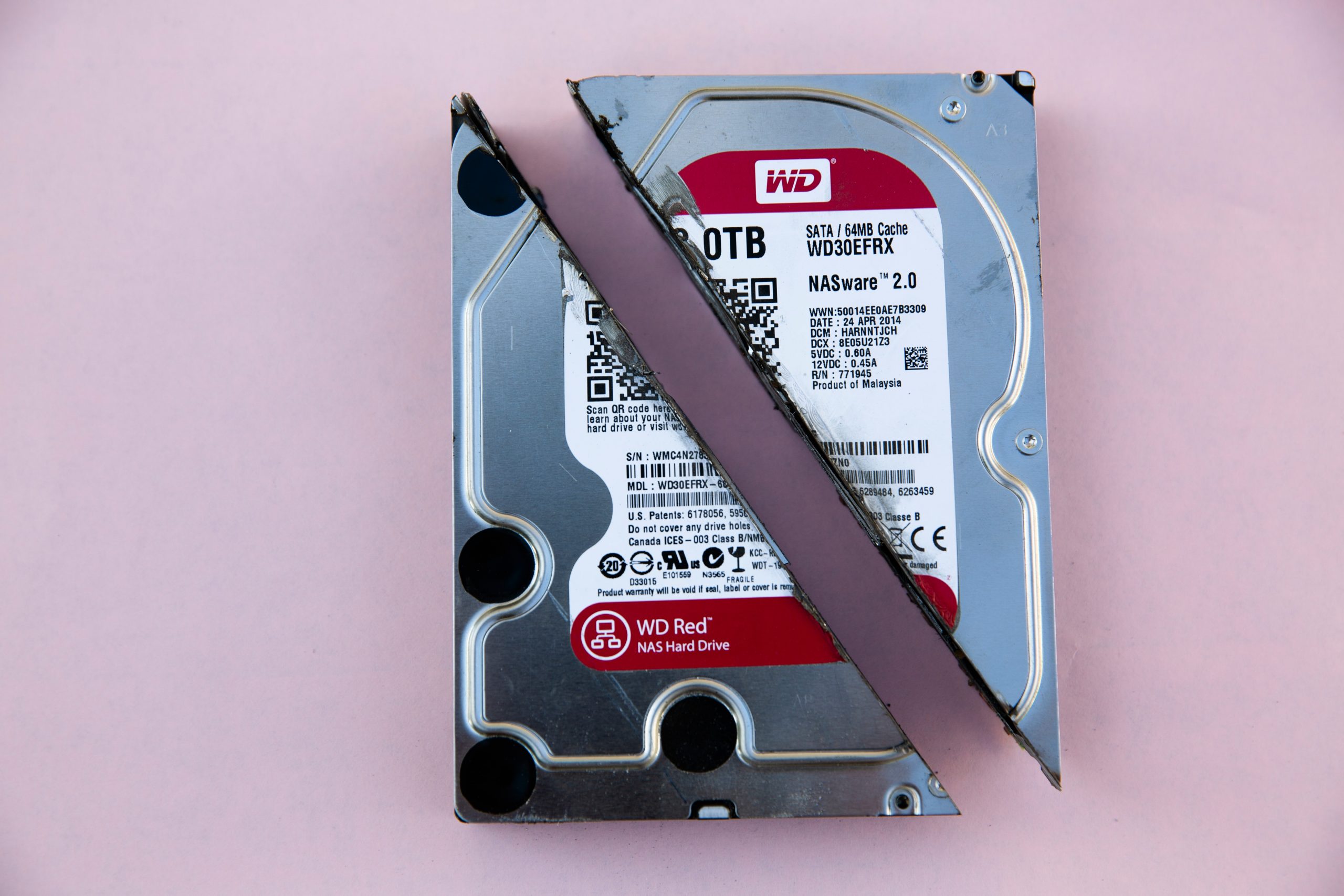 Western Digital WD Red internal HDD sliced in half on pink surface